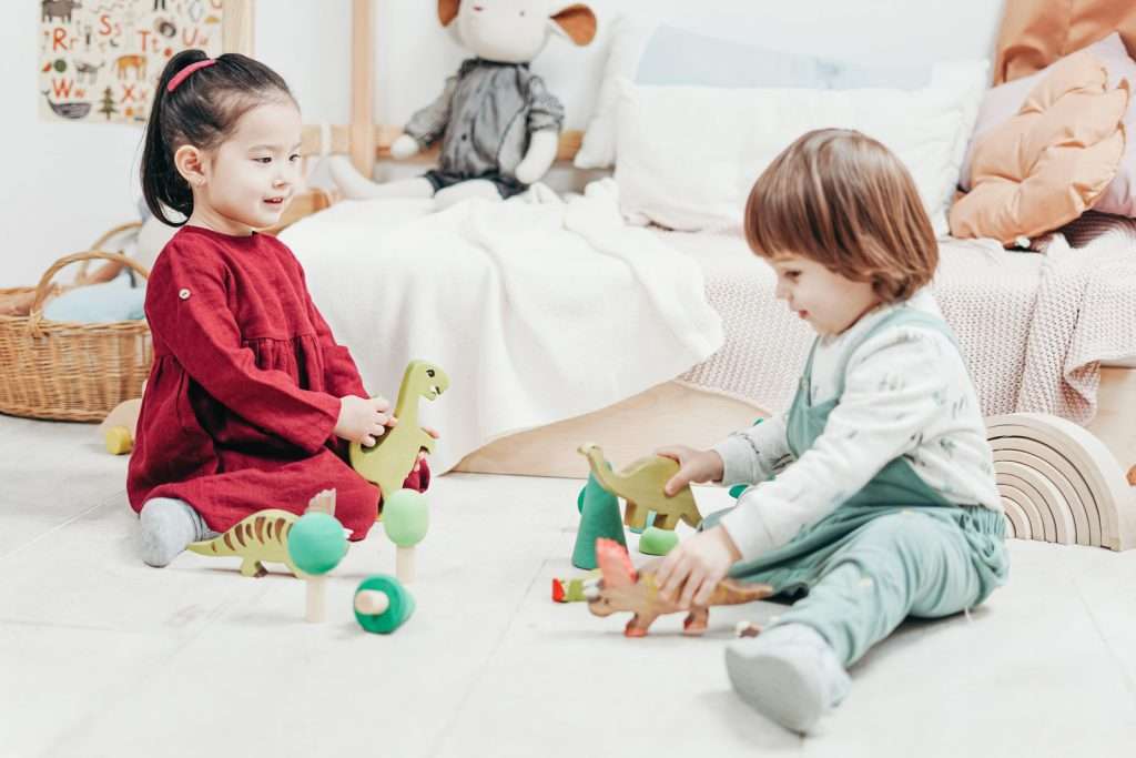 Two Children Sitting Down Playing With Toys