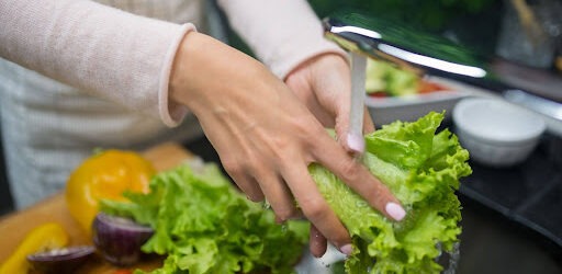 Person washing vegetables under the faucet